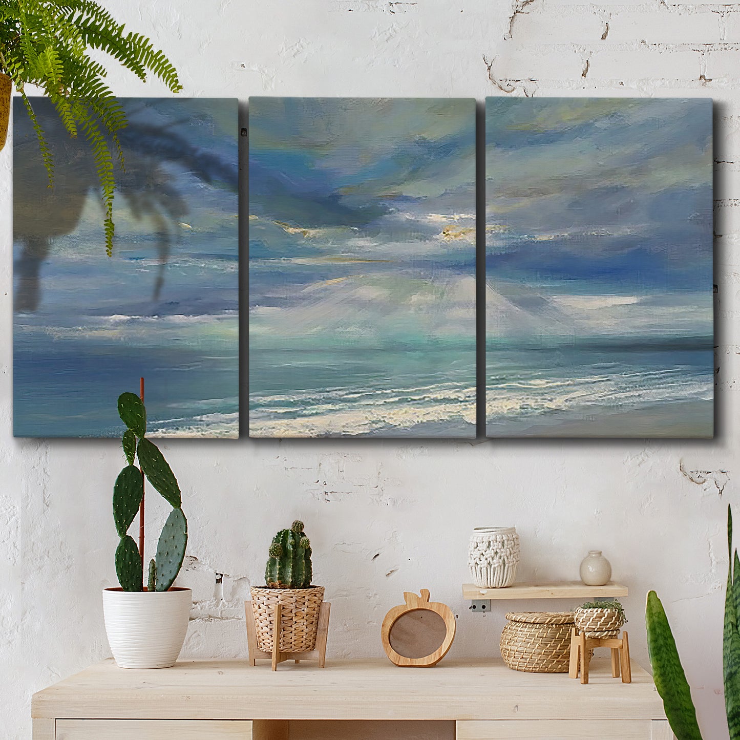 Three-panel canvas wall art featuring sunbeams breaking through coastal clouds, displayed in a boho-chic entryway above a console table.