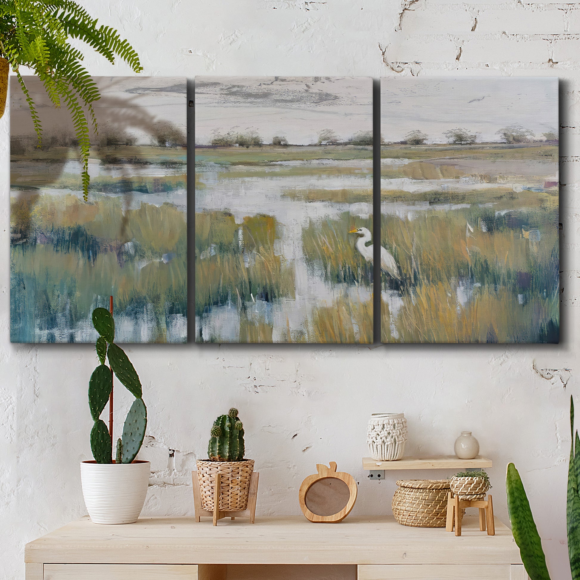 Three-panel canvas wall art featuring pastoral marshland landscape, displayed in a boho-chic entryway above a console table.