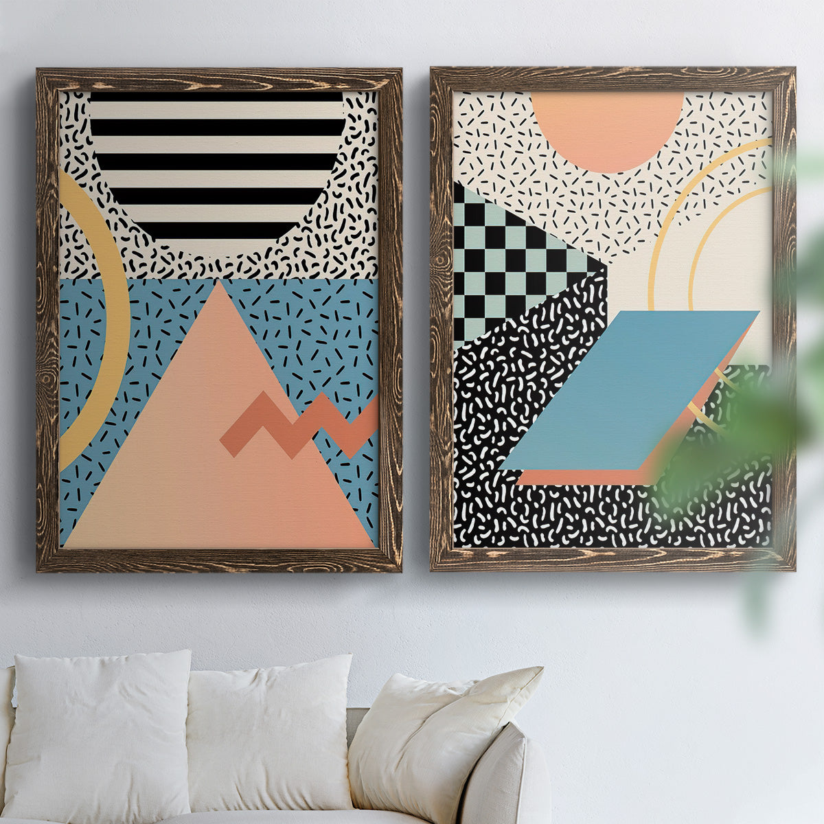 Set of two walnut barnwood framed canvas prints depicting checkerboards stripes squiggles peach blue black and mint shapes arranged across two complementary compositions above a sofa in a bright living space.