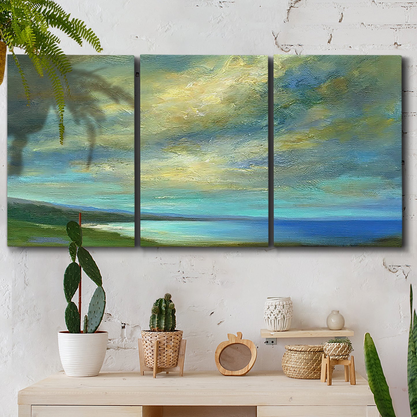 Three-panel canvas wall art featuring coastal shoreline with soft waves, displayed in a boho-chic entryway above a console table.