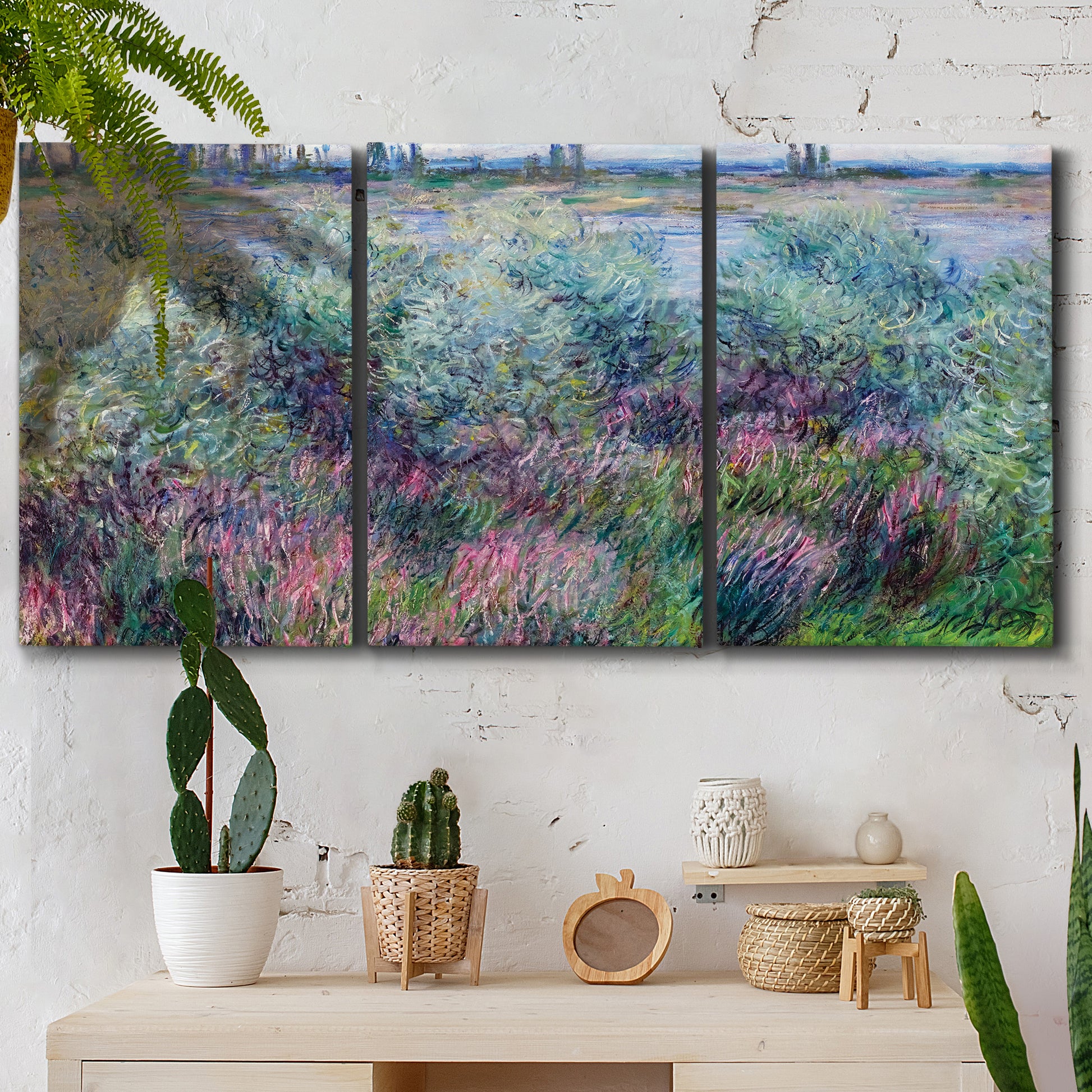 Three-panel canvas wall art featuring flowered riverbank with trees, displayed in a boho-chic entryway above a console table.