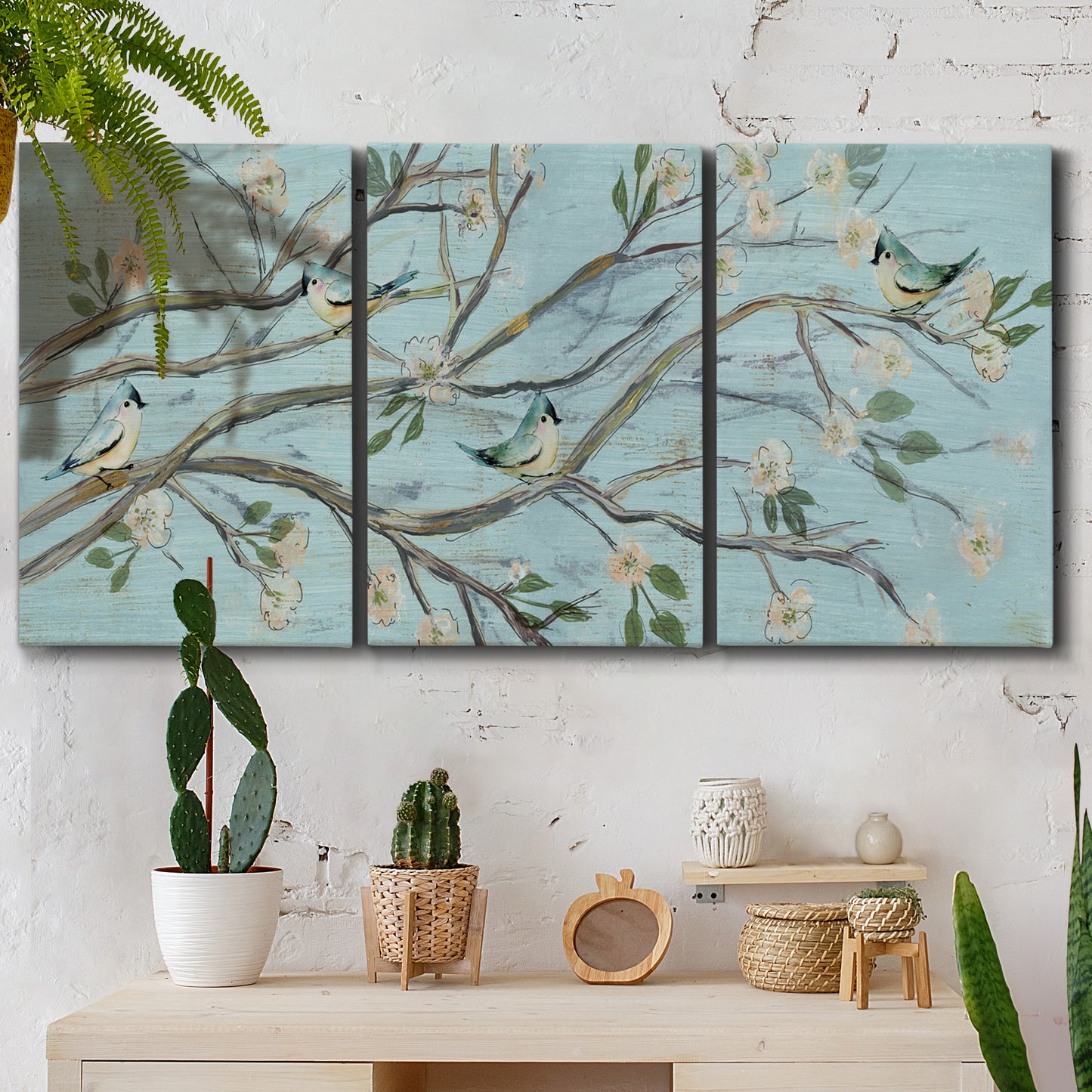 Three-panel canvas wall art featuring blue sky with flowering branches, displayed in a boho-chic entryway above a console table.