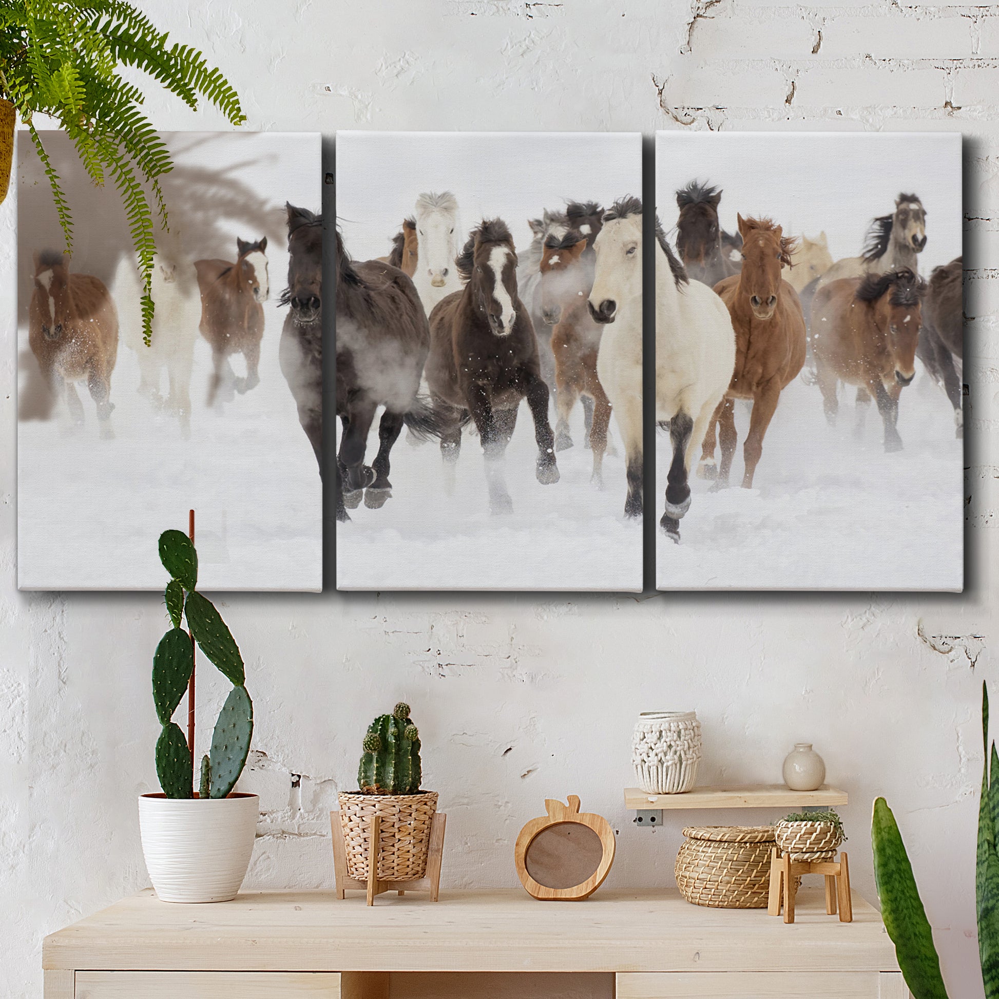 Three-panel canvas wall art featuring horses running across snowy pasture, displayed in a boho-chic entryway above a console table.