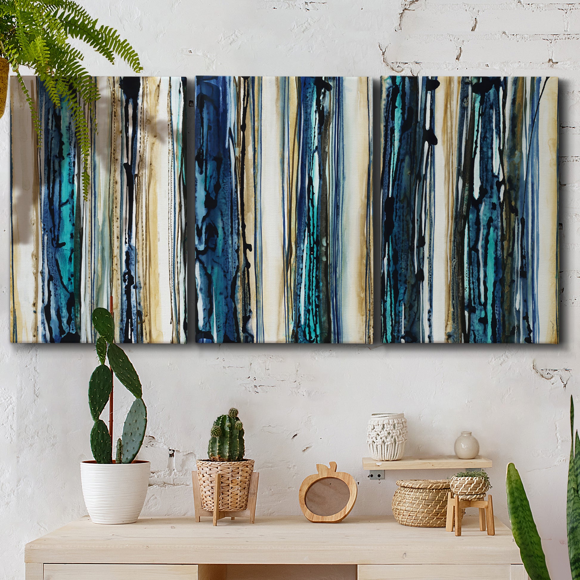 Three-panel canvas wall art featuring vertical blue abstract streaks, displayed in a boho-chic entryway above a console table.