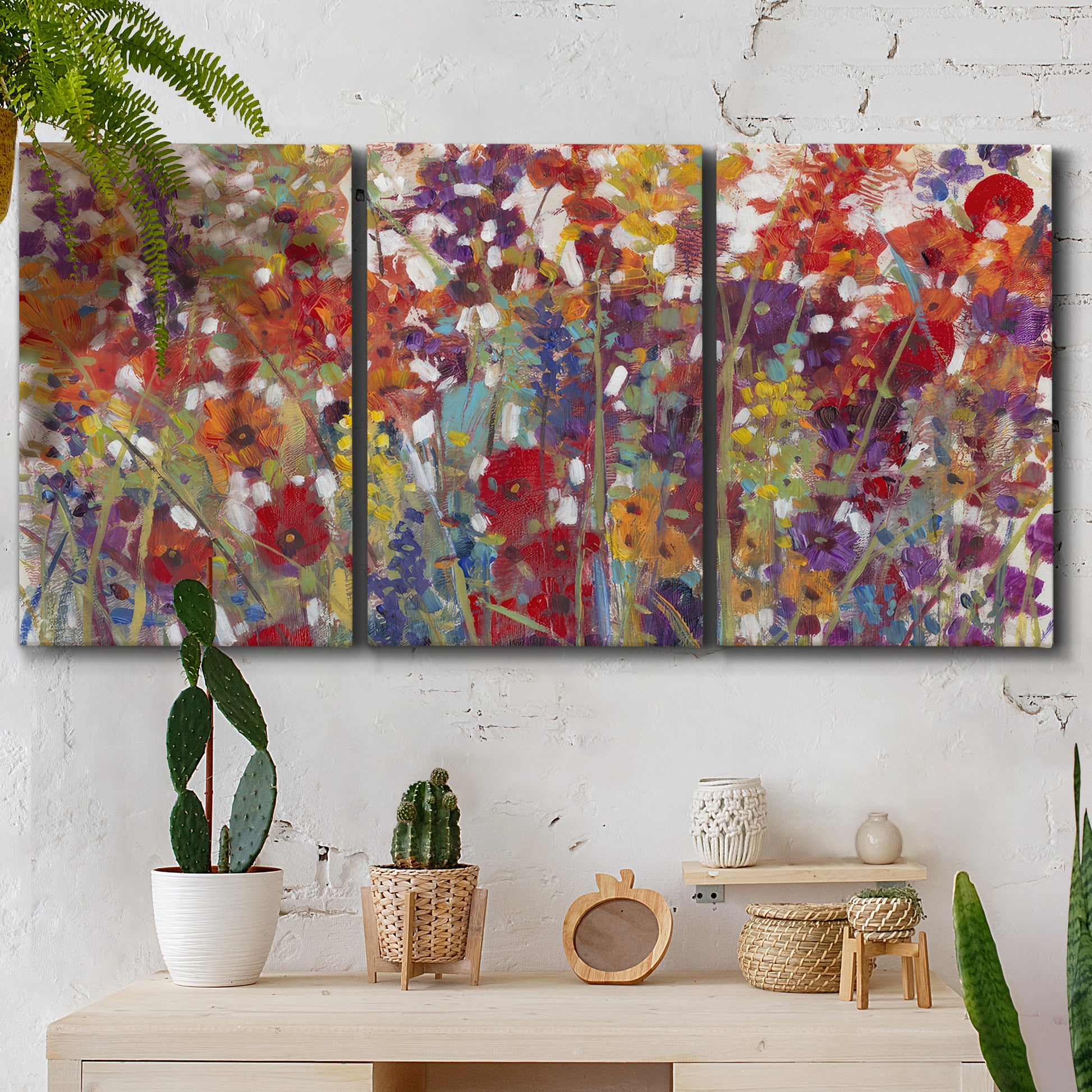 Three-panel canvas wall art featuring colorful floral arrangement, displayed in a boho-chic entryway above a console table.