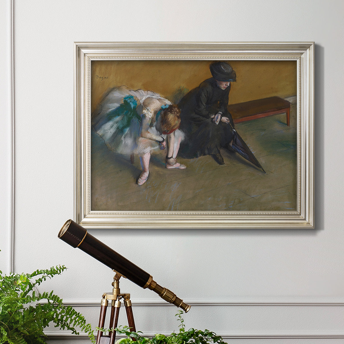 Impressionist portrait of a seated woman by Edgar Degas in an ornate champagne frame displayed in a light-toned interior setting.