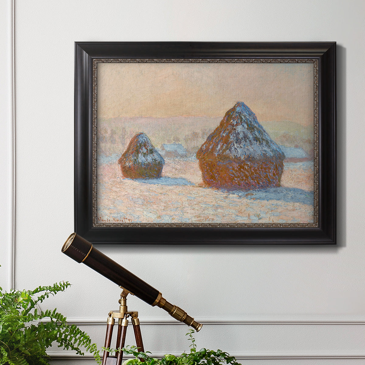Impressionist winter haystack scene by Claude Monet in an ornate black frame with gilded inner detail displayed in a light-toned interior setting.