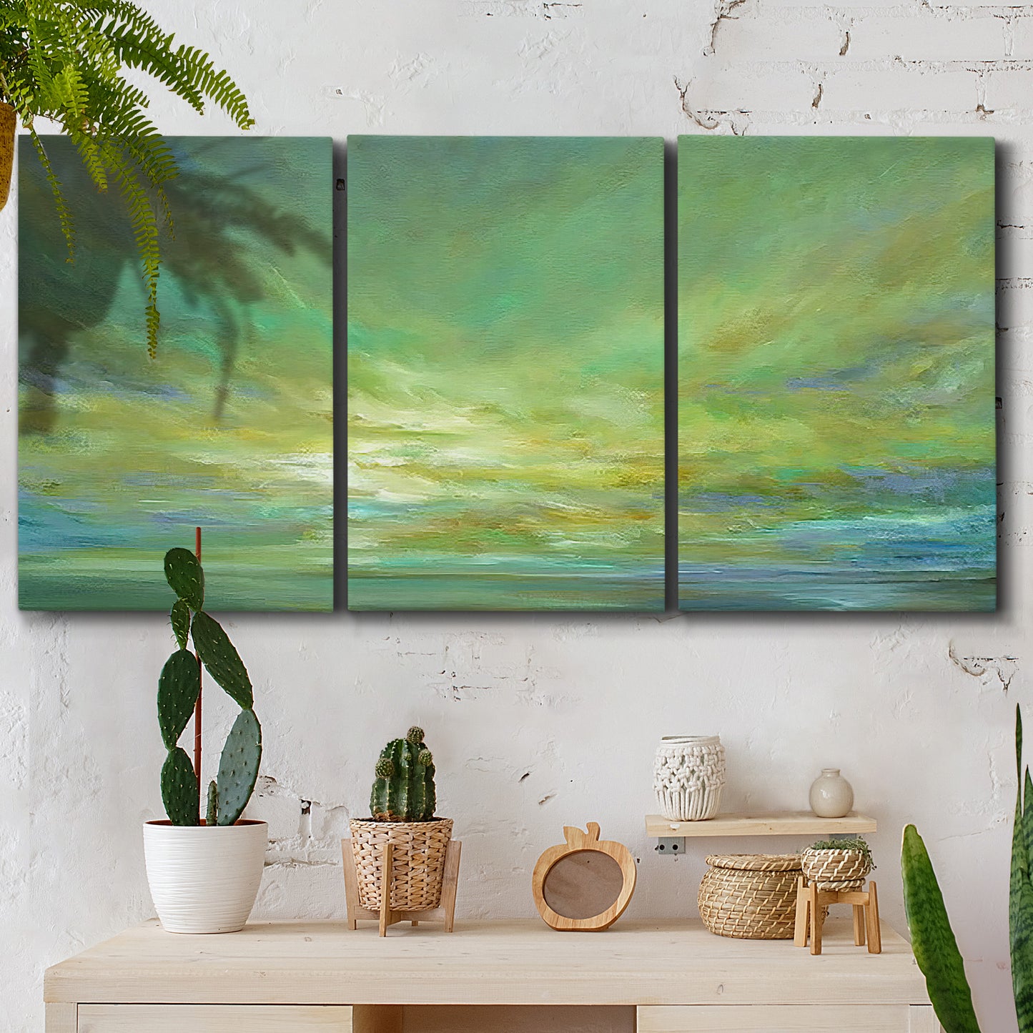 Three-panel canvas wall art featuring coastal shoreline under open sky, displayed in a boho-chic entryway above a console table.