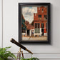 Realist city street scene by Johannes Vermeer in an ornate black frame with gilded inner detail displayed in a light-toned interior setting.