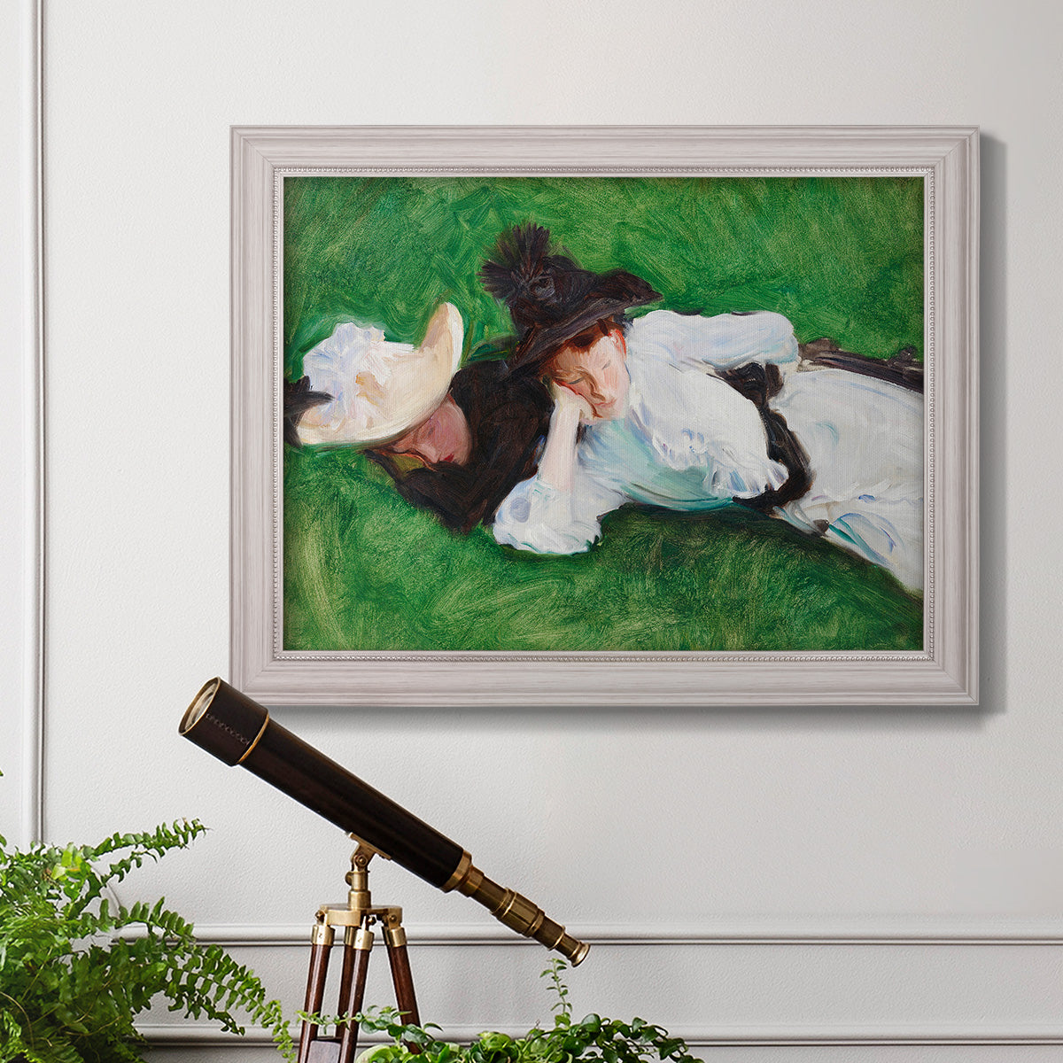 Impressionist outdoor portrait of two girls by John Singer Sargent in an ornate weathered white frame displayed in a light-toned interior setting.
