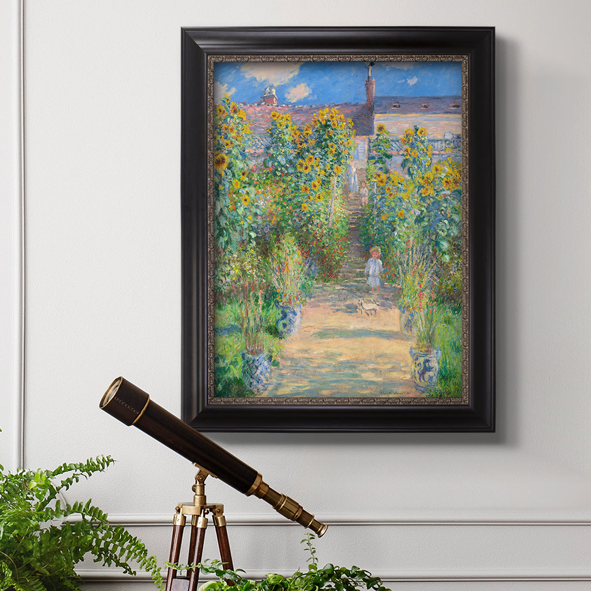 Impressionist garden landscape painting by Claude Monet in an ornate black frame with gilded inner detail displayed in a light-toned interior setting.