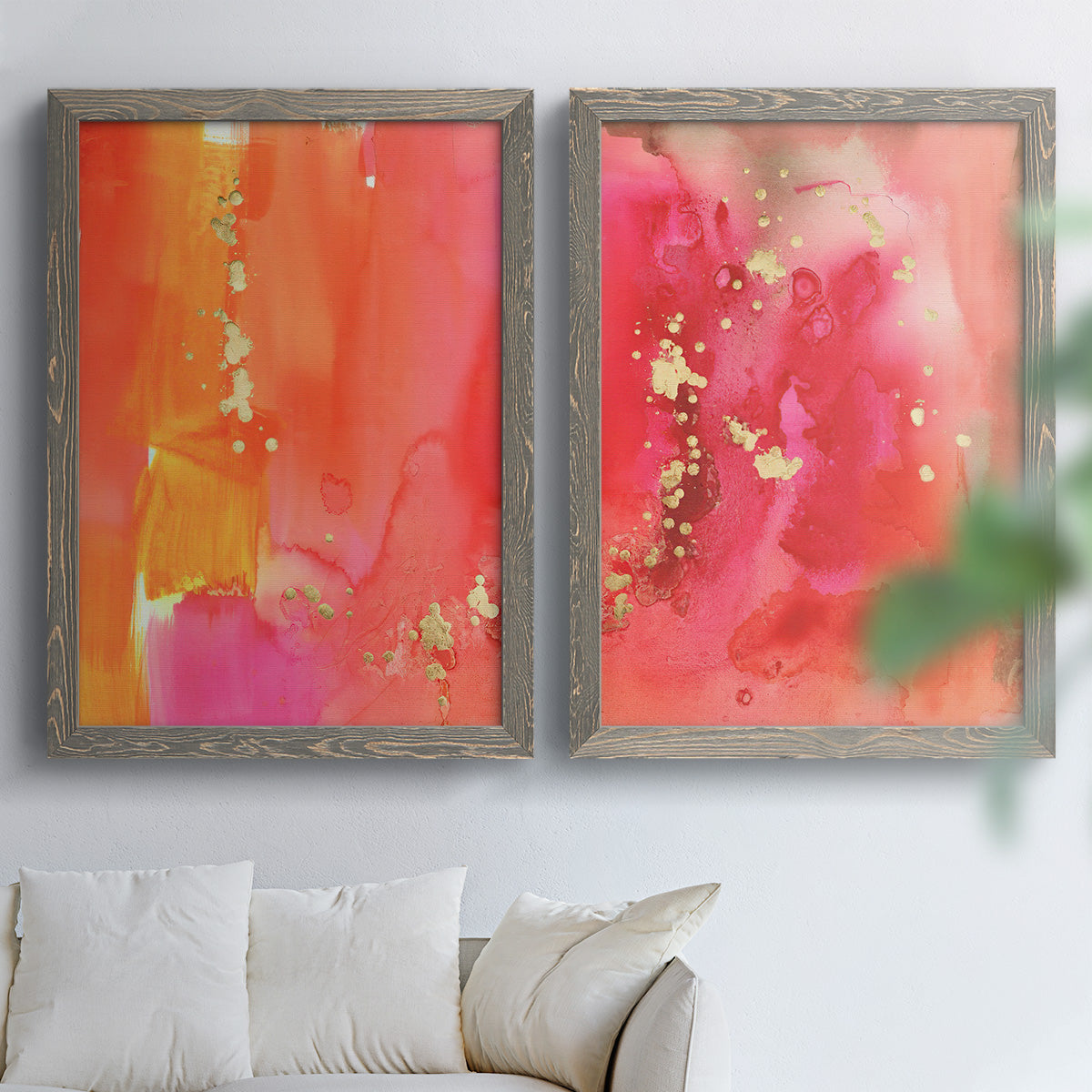 Set of two gray barnwood framed canvas prints depicting translucent warm washes, drips, and scattered metallic accents arranged across two complementary compositions above a sofa in a bright living space.