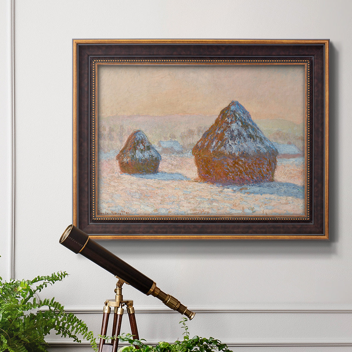 Impressionist winter haystack scene by Claude Monet in an ornate bronzed mahogany wood frame displayed in a light-toned interior setting.