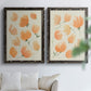 Set of two black barnwood framed canvas prints depicting soft petals, thin black stems, and warm cream backgrounds arranged across two complementary compositions above a sofa in a bright living space.