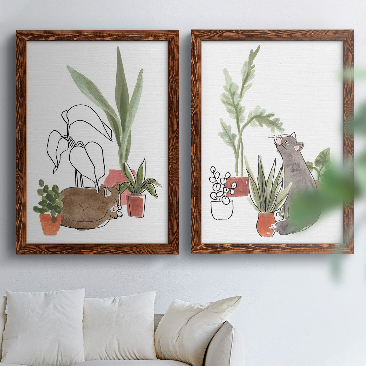 Set of two maple barnwood framed canvas prints depicting curious felines, terracotta pots, succulents, and leafy stems arranged across two complementary compositions above a sofa in a bright living space.
