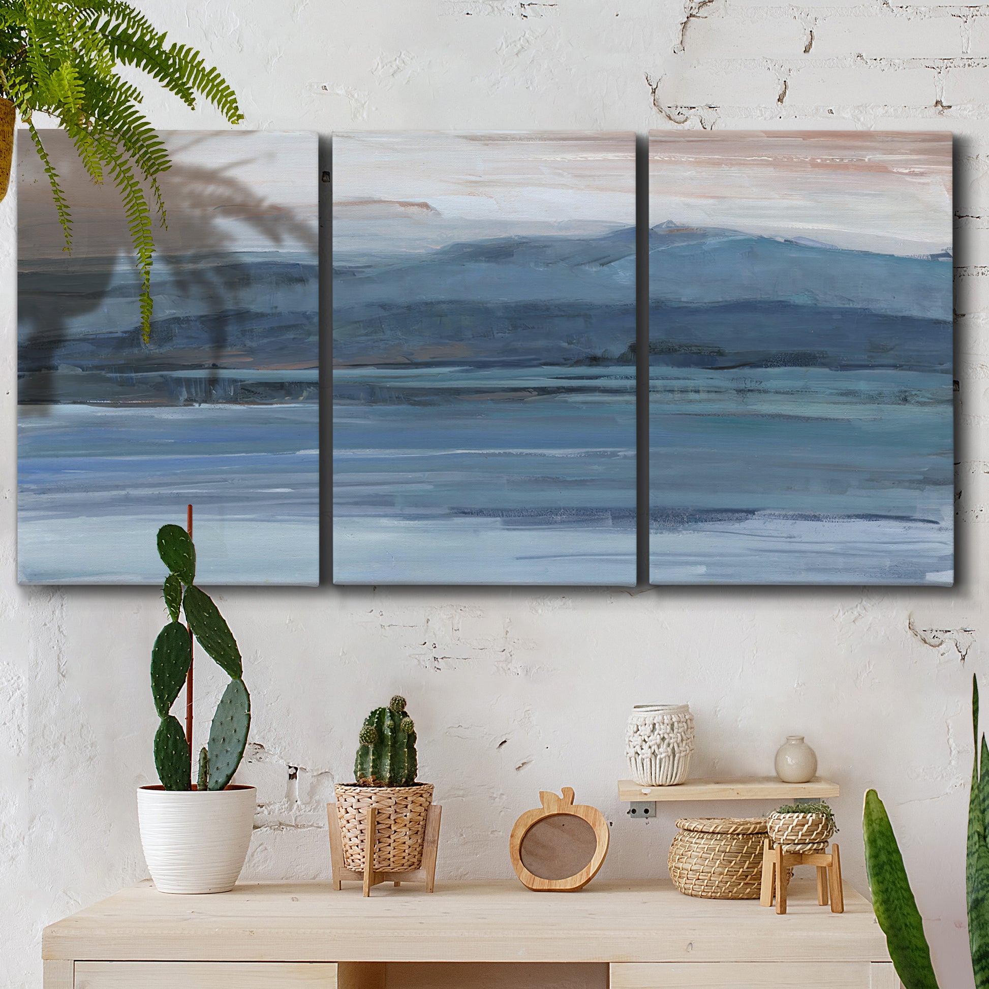 Three-panel canvas wall art featuring wide lake with distant shoreline, displayed in a boho-chic entryway above a console table.