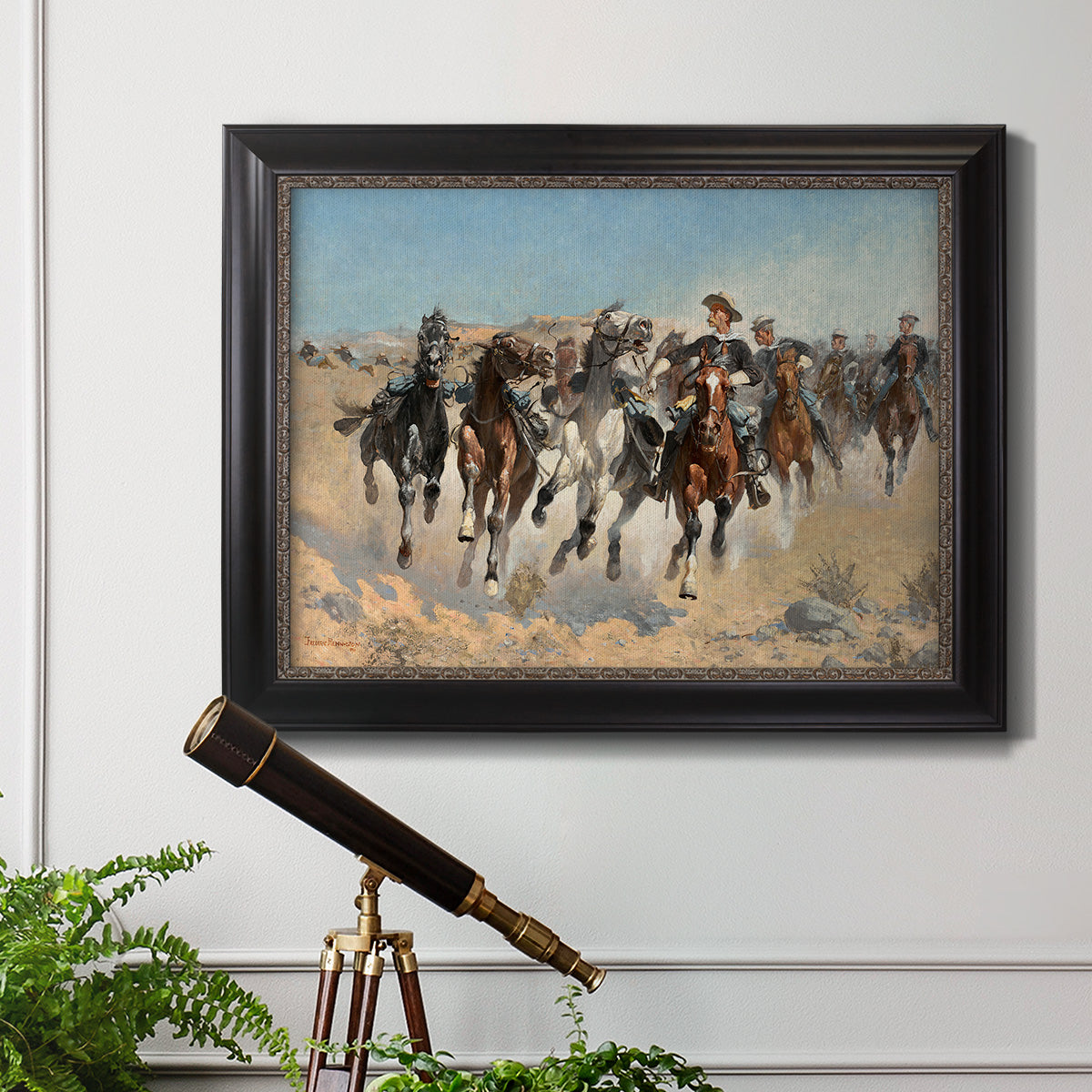 Impressionist western action scene by Frederic Remington in an ornate black frame with gilded inner detail displayed in a light-toned interior setting.