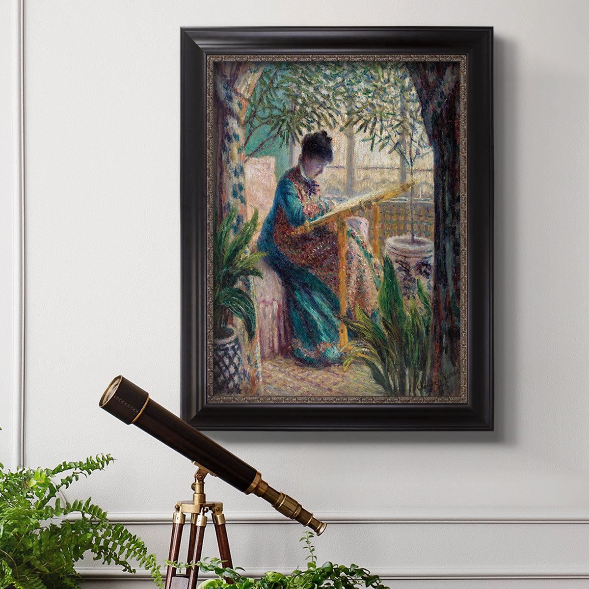 Impressionist portrait of Madame Monet sewing by Claude Monet in an ornate black frame with gilded inner detail displayed in a light-toned interior setting.