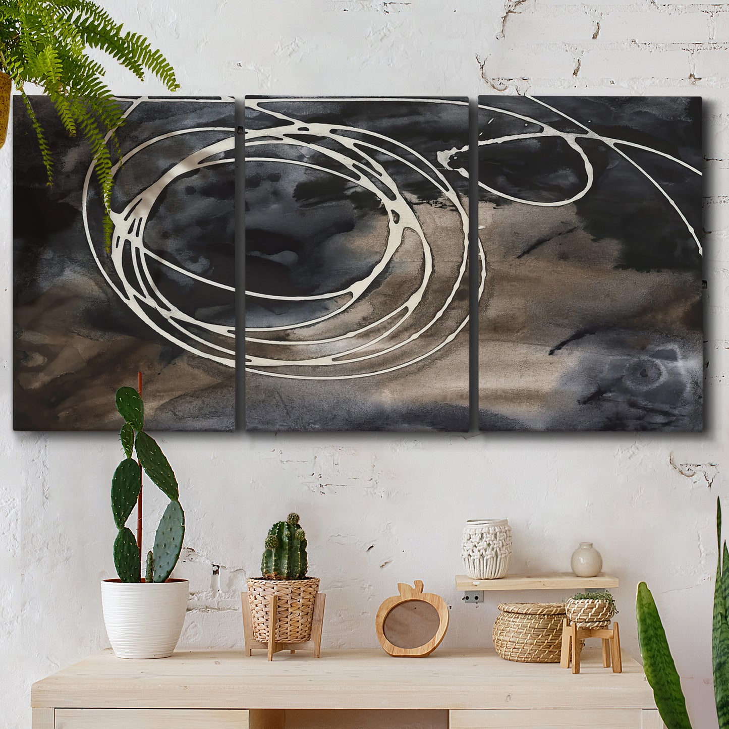 Three-panel canvas wall art featuring dark swirling abstract motion, displayed in a boho-chic entryway above a console table.