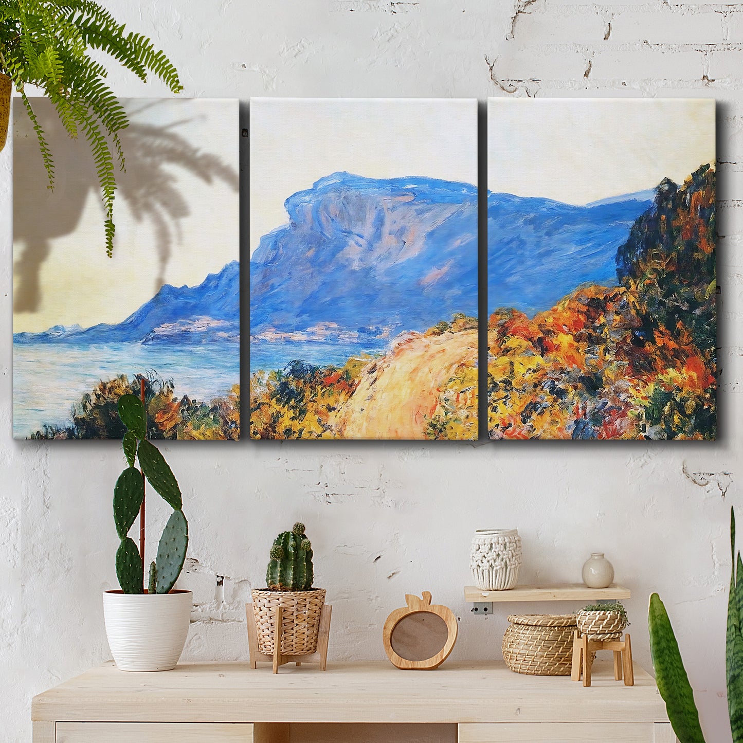 Three-panel canvas wall art featuring winding red road hillside, displayed in a boho-chic entryway above a console table.