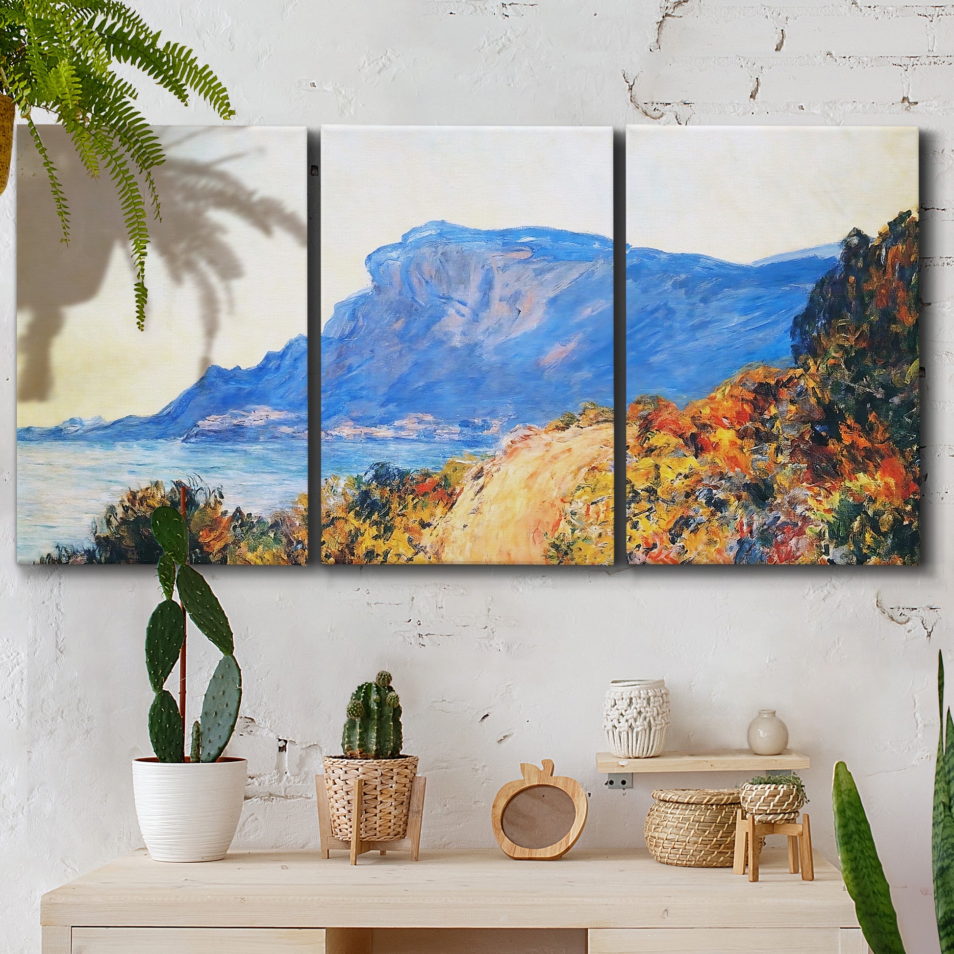 Three-panel canvas wall art featuring winding red road hillside, displayed in a boho-chic entryway above a console table.