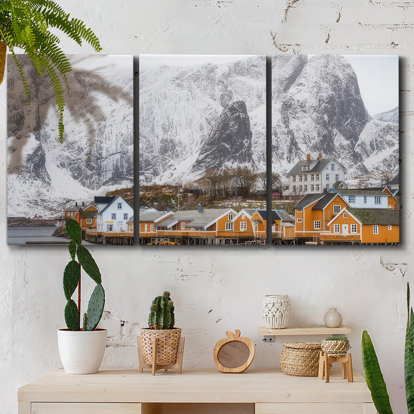 Three-panel canvas wall art featuring winter village street photography, displayed in a boho-chic entryway above a console table.