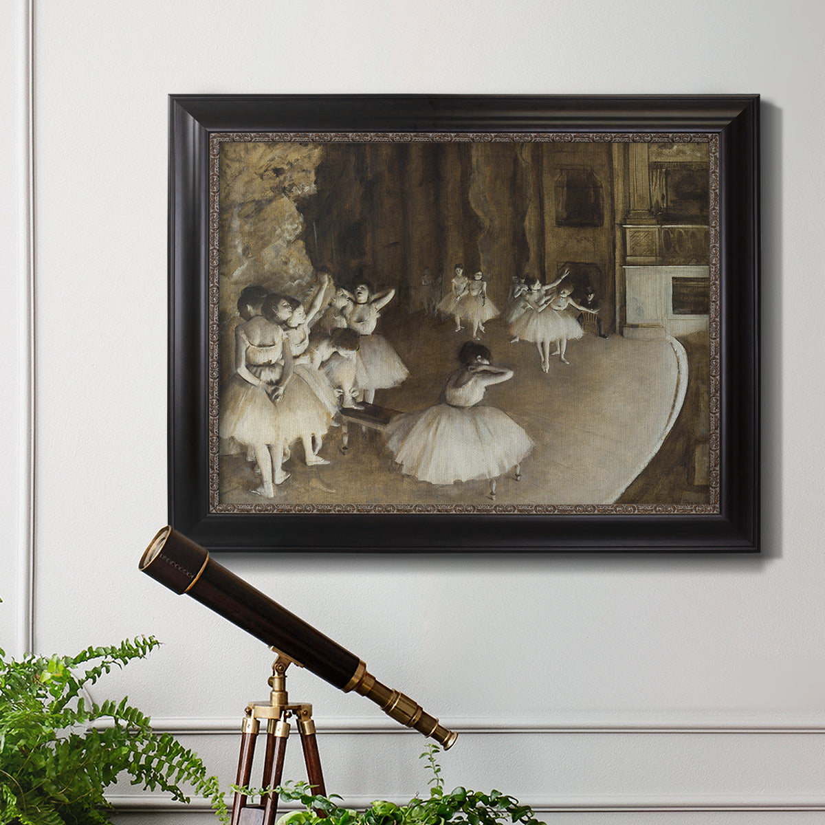 Impressionist ballet rehearsal scene by Edgar Degas in an ornate black frame with gilded inner detail displayed in a light-toned interior setting.