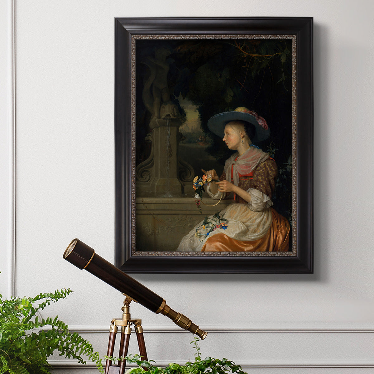 Classical interior scene of a woman weaving flowers by Godfried Schalcken in an ornate black frame with gilded inner detail displayed in a light-toned interior setting.