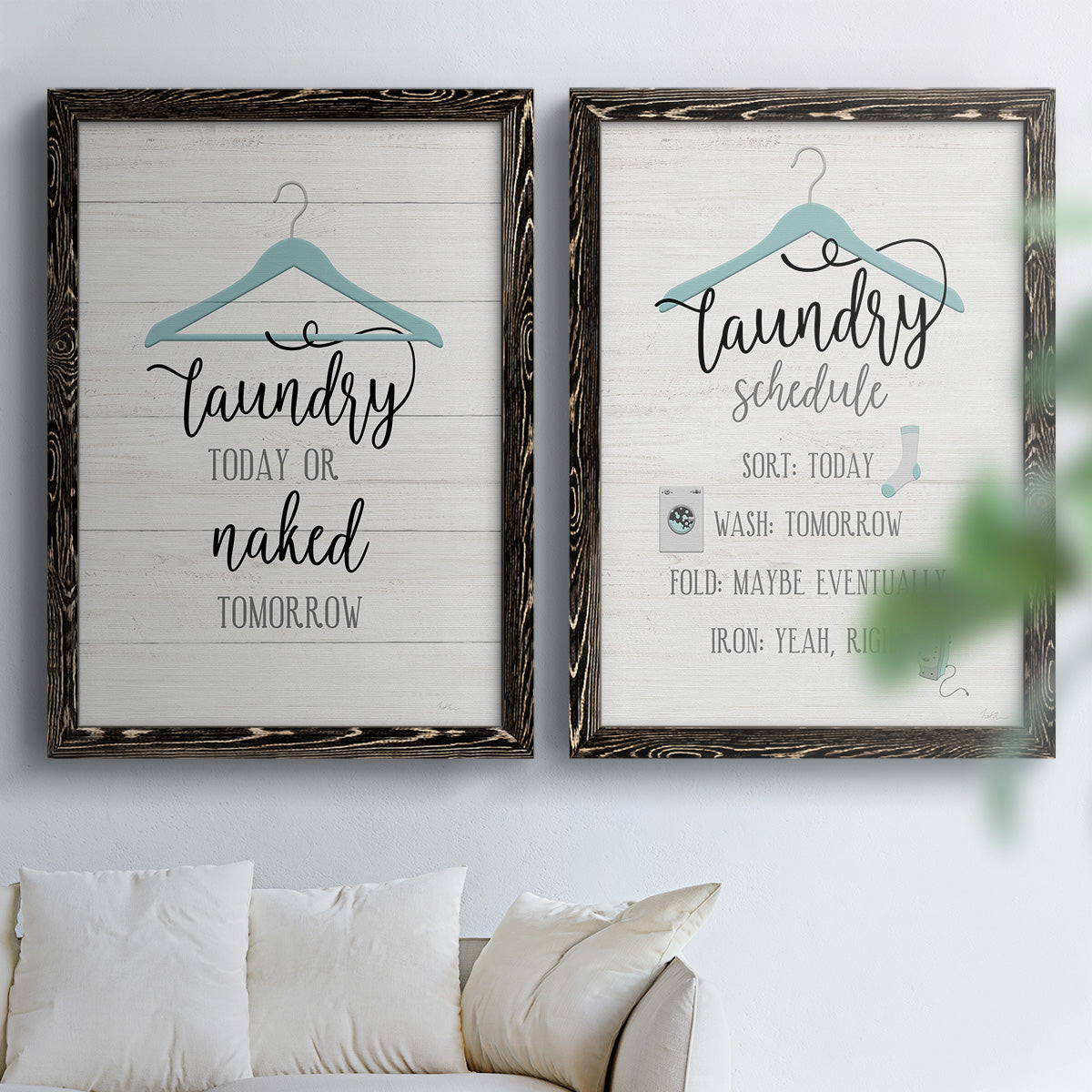 Set of two black barnwood framed canvas prints depicting hand-lettered phrases, socks hangers and laundry symbols on linen texture arranged across two complementary compositions above a sofa in a bright living space.