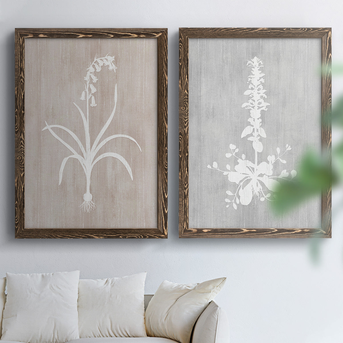 Set of two walnut barnwood framed canvas prints depicting delicate stems, leaves, and blossoms against gray taupe and pale blue panels arranged across two complementary compositions above a sofa in a bright living space.