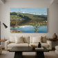 Canvas art print featuring an expansive view of land and water beneath approaching storm clouds, displayed in a spacious living room