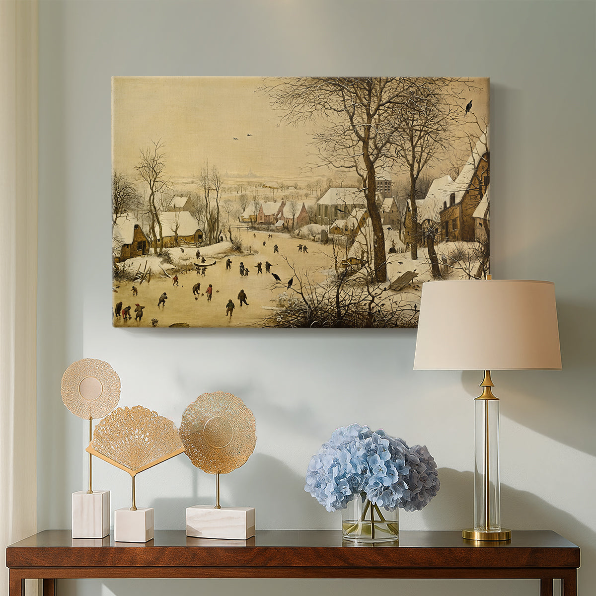 Canvas art print featuring a rustic village scene with skaters and snow-covered terrain, displayed above a styled console table