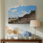 Canvas art print featuring a sandy beach with figures relaxing near water's edge, displayed above a styled console table