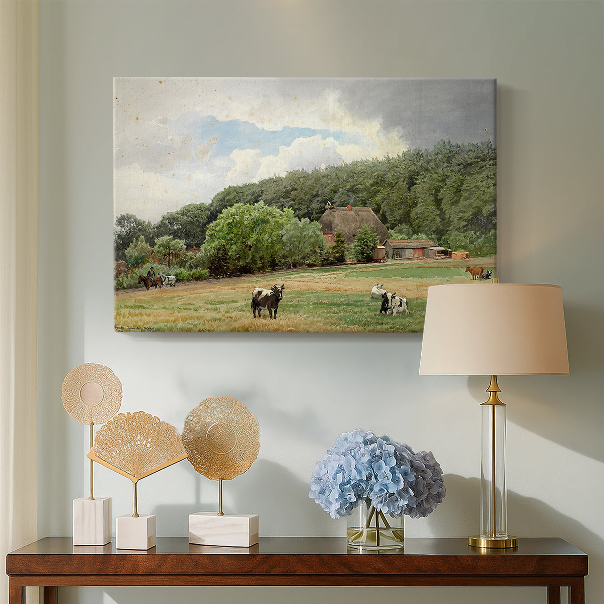 Canvas art print featuring a rural landscape with cows feeding on grass near buildings, displayed above a styled console table