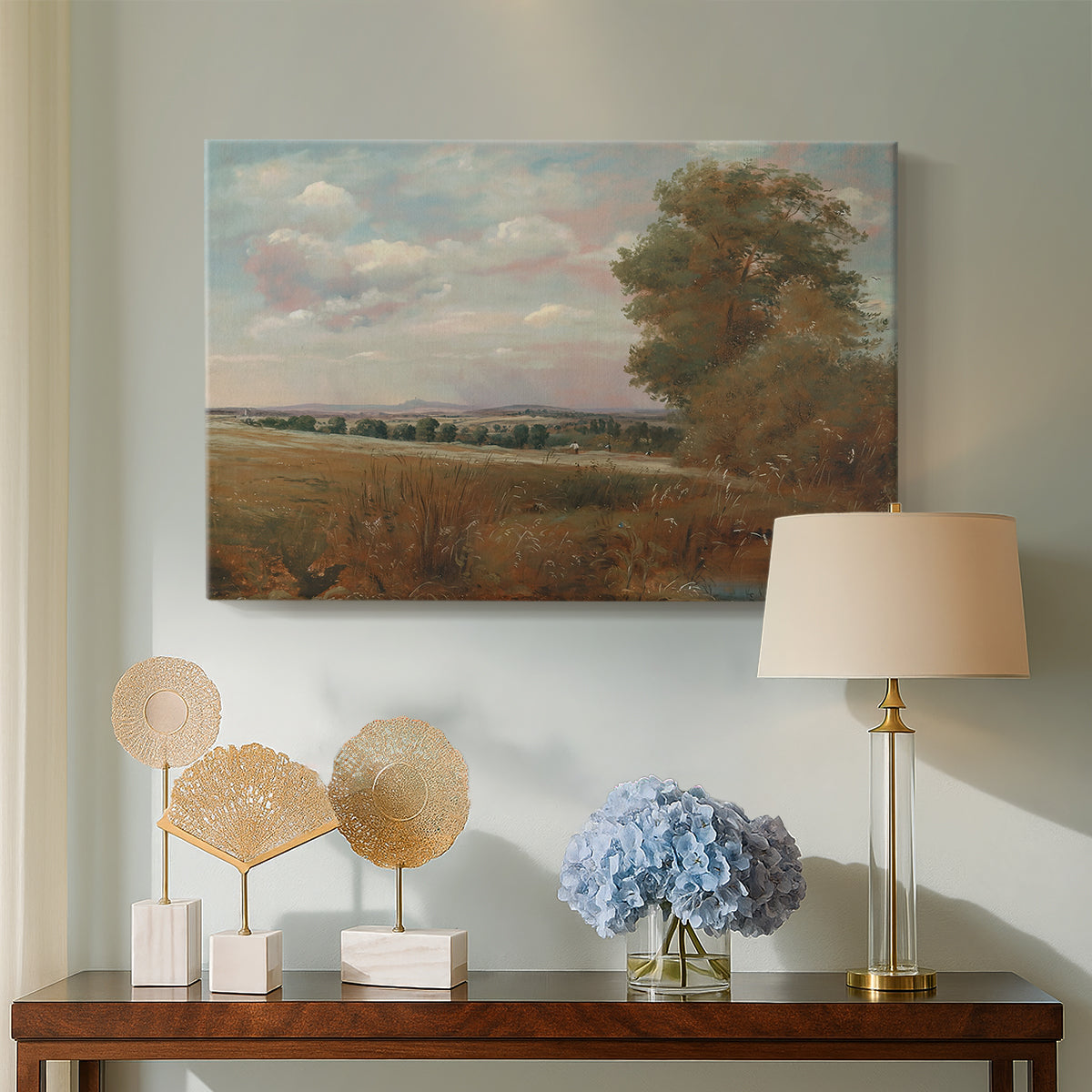 Canvas art print featuring a countryside scene with distant town, displayed above a styled console table