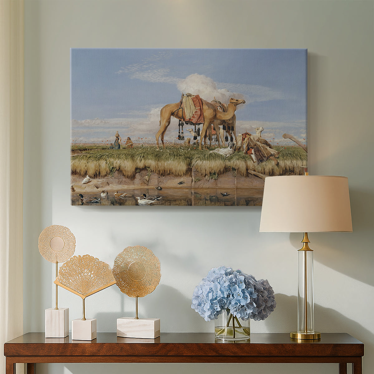 Canvas art print featuring a landscape featuring river, animals, and activity, displayed above a styled console table
