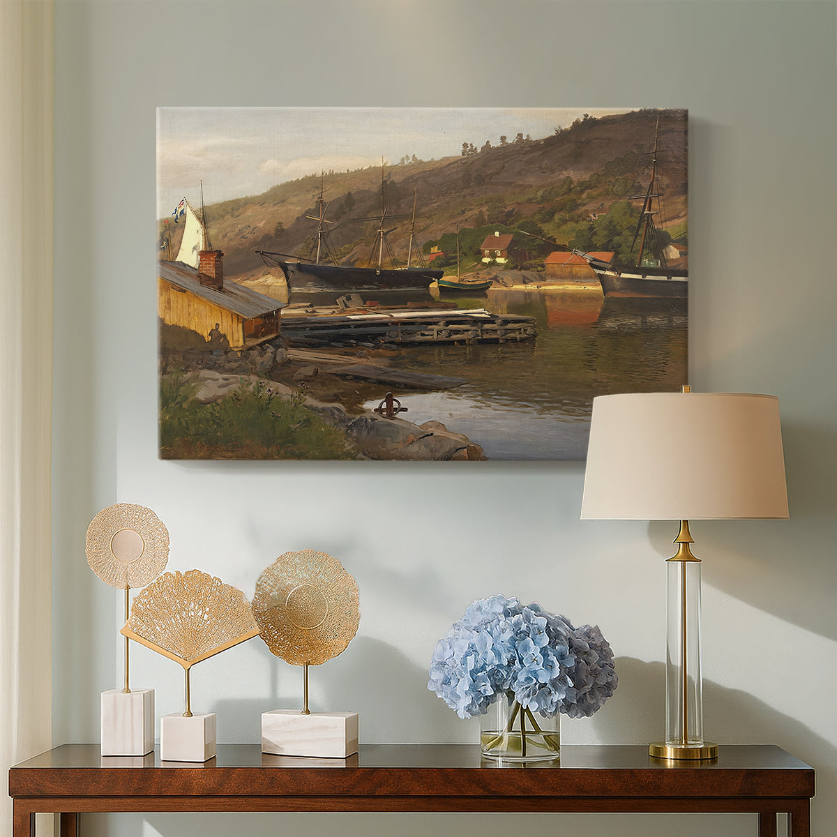 Canvas art print featuring a waterfront setting with village structures and reflections, displayed above a styled console table