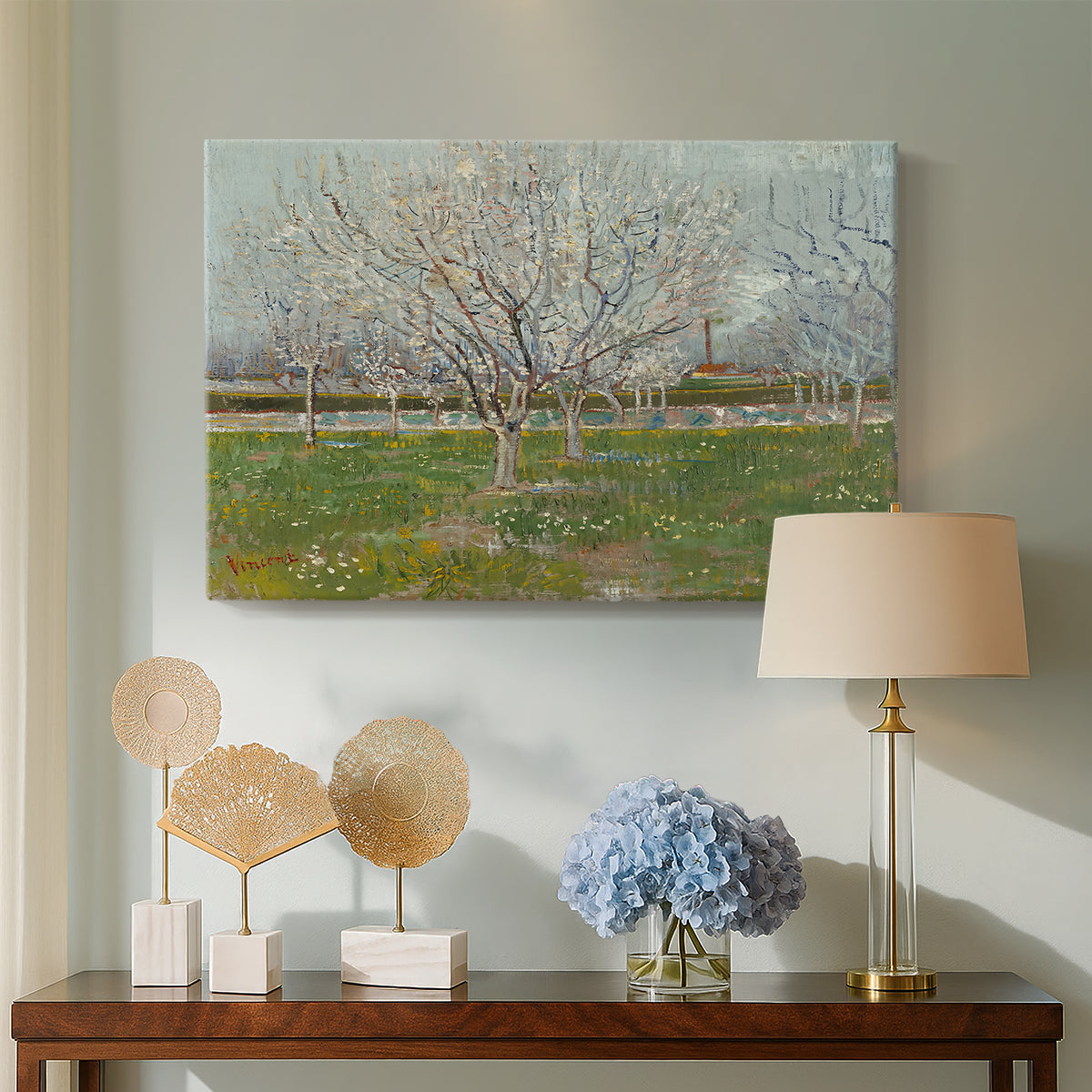 Canvas art print featuring an orchard composition with pale blossoms against open sky, displayed above a styled console table