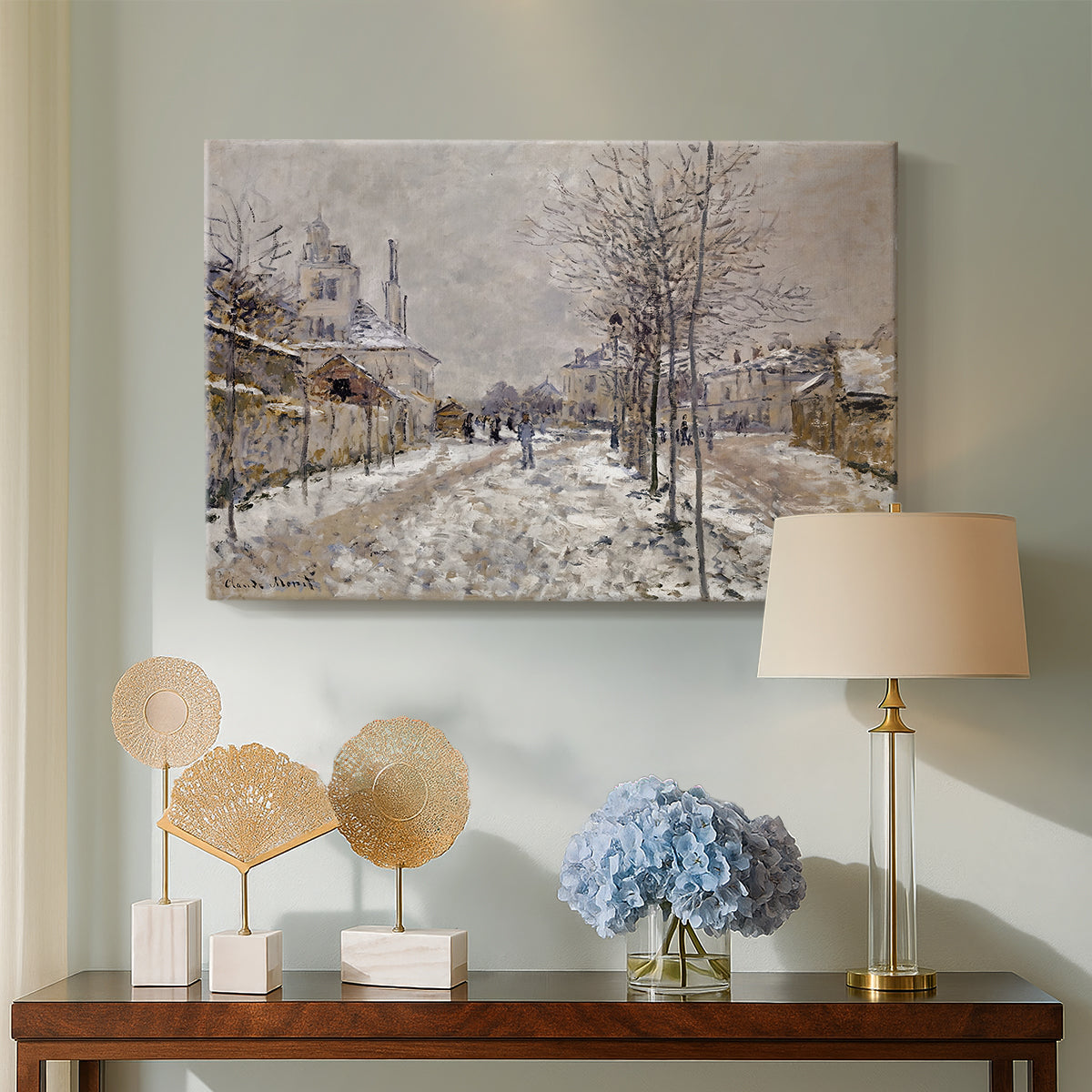 Canvas art print featuring a quiet boulevard blanketed in snow with distant figures, displayed above a styled console table
