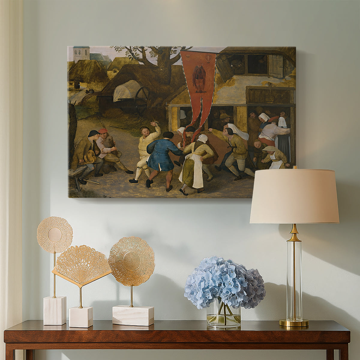 Canvas art print featuring a lively village gathering with multiple figures interacting, displayed above a styled console table