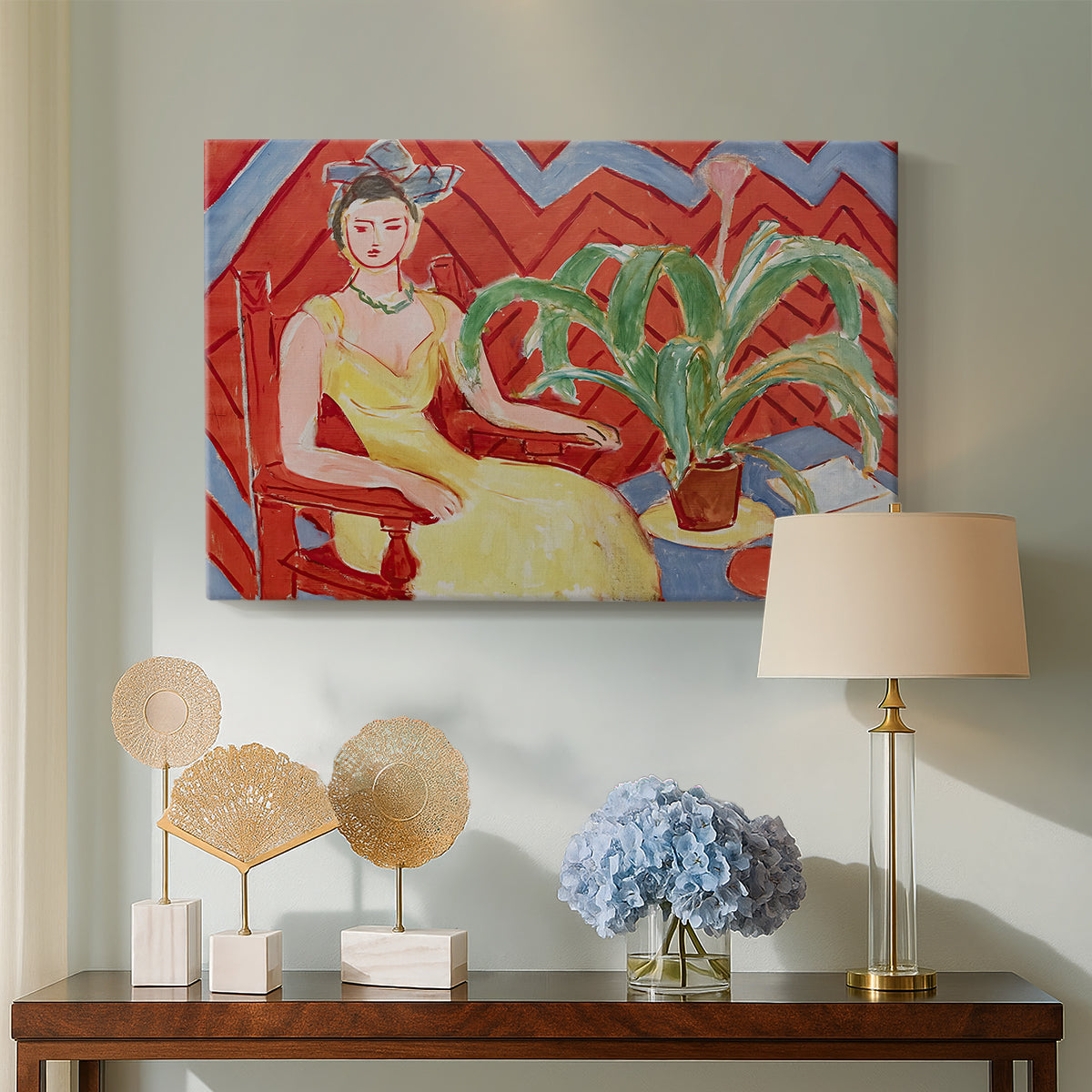 Canvas art print featuring a stylized seated female figure in strong warm tones, displayed above a styled console table