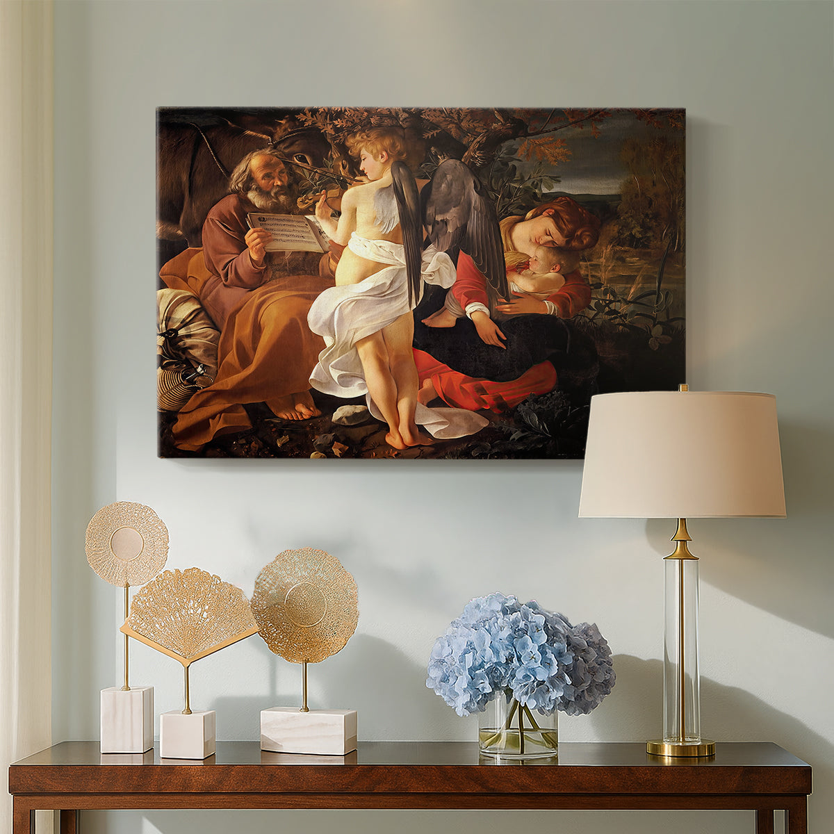 Canvas art print featuring a peaceful religious moment with figures reclining in natural setting, displayed above a styled console table