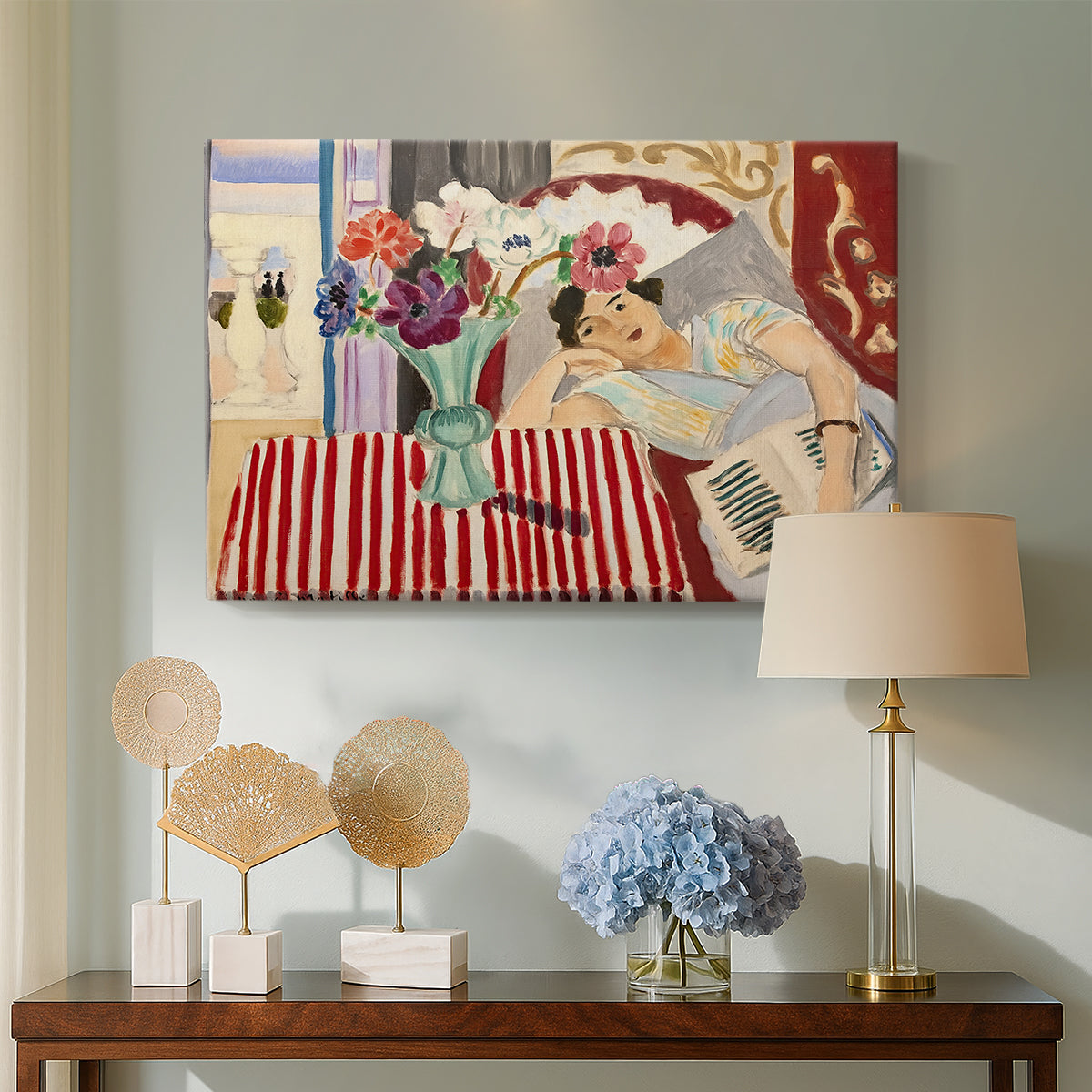Canvas art print featuring an expressive interior with woman and bright flowers on table, displayed above a styled console table
