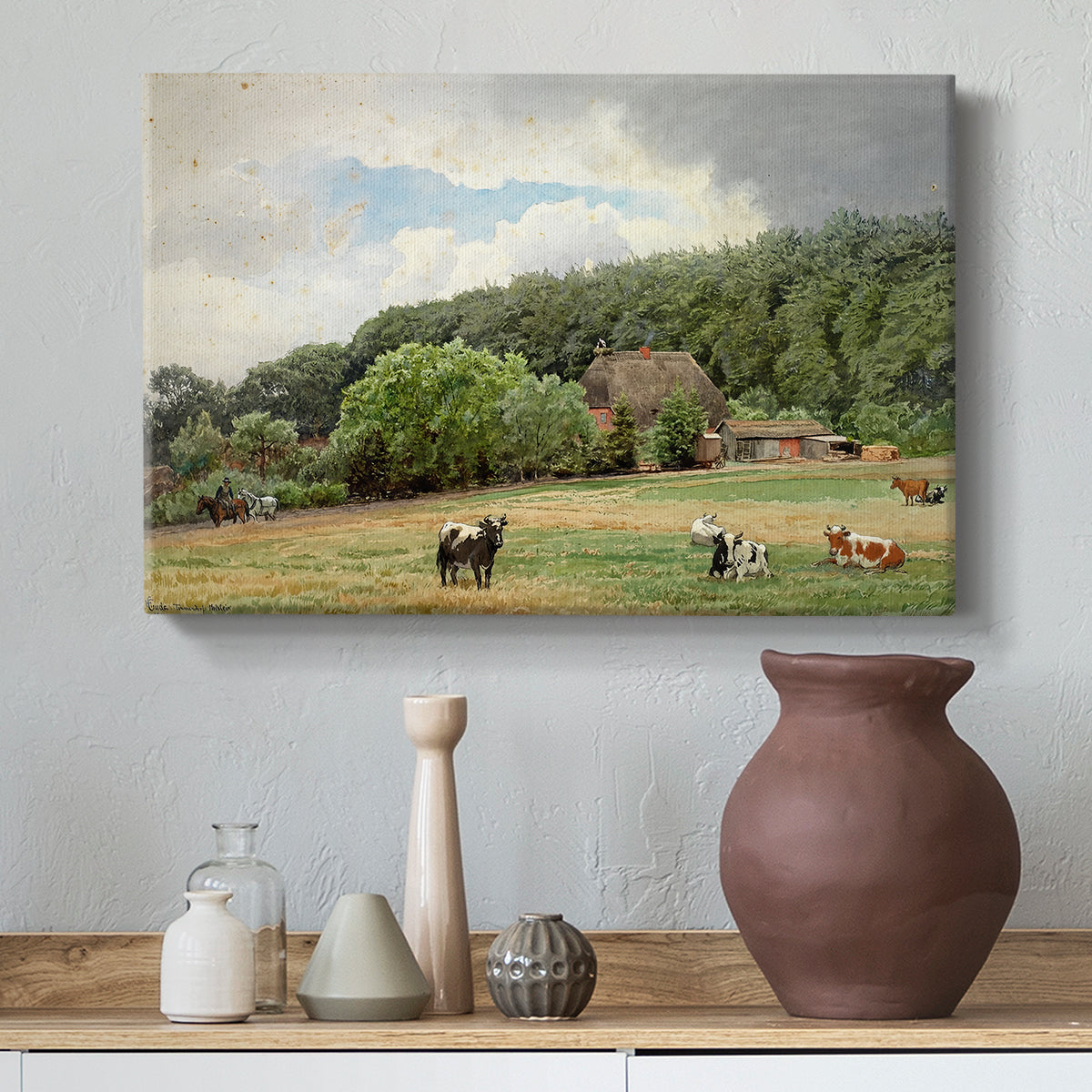 Canvas art print featuring a rural landscape with cows feeding on grass near buildings, styled above a decorative console