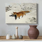 Canvas art print featuring a red fox crossing snow-covered ground under pale sky, styled above a decorative console