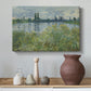 Canvas art print featuring a tranquil riverside scene with houses and vegetation, styled above a decorative console