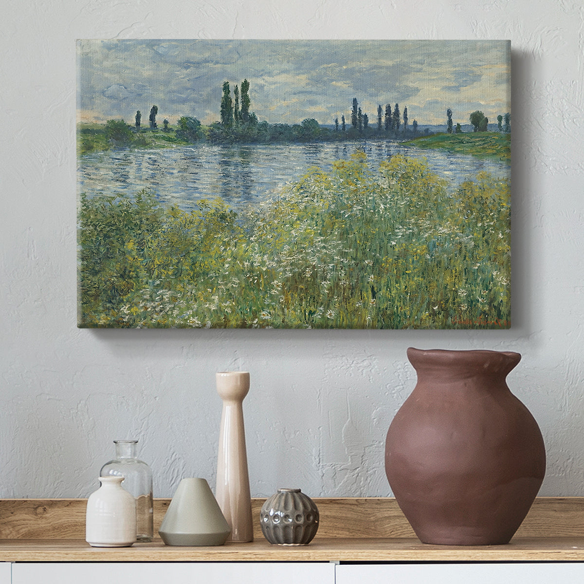 Canvas art print featuring a tranquil riverside scene with houses and vegetation, styled above a decorative console