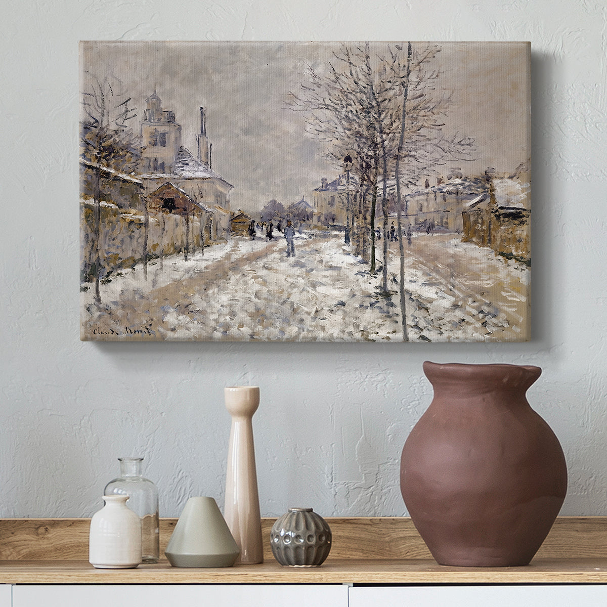 Canvas art print featuring a quiet boulevard blanketed in snow with distant figures, styled above a decorative console