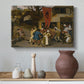 Canvas art print featuring a lively village gathering with multiple figures interacting, styled above a decorative console