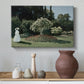 Canvas art print featuring an elegant woman posed outdoors among blooming plants, styled above a decorative console